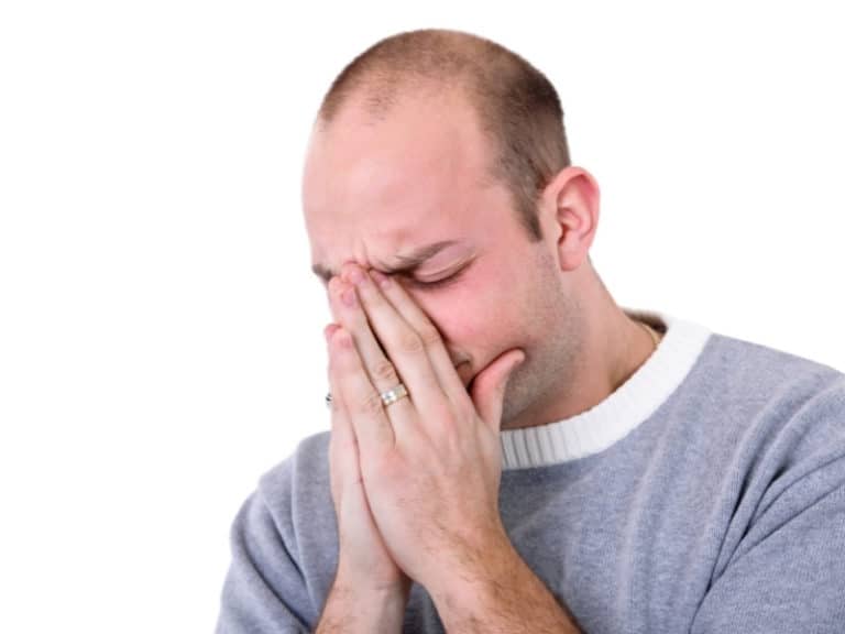 man holding nose in pain